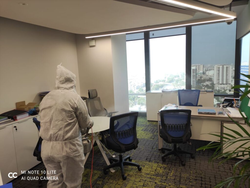 Pest Orbit technician in protective coveralls treating an office interior